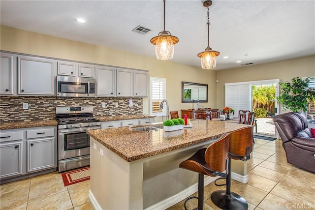 kitchen featuring stainless steel appliances, gray cabinets, visible vents, backsplash, and a sink