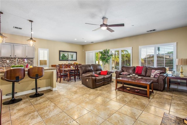 living room featuring ceiling fan, visible vents, baseboards, and light tile patterned flooring