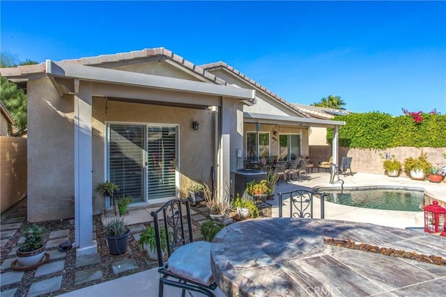 rear view of property with a fenced in pool, a fenced backyard, outdoor dining area, a patio area, and stucco siding