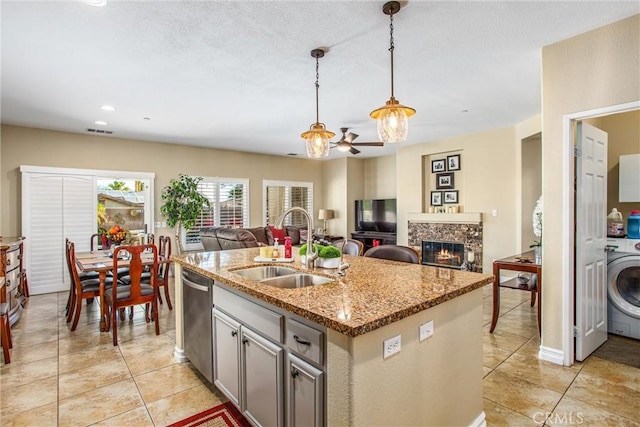 kitchen with hanging light fixtures, stainless steel dishwasher, a high end fireplace, open floor plan, and a sink