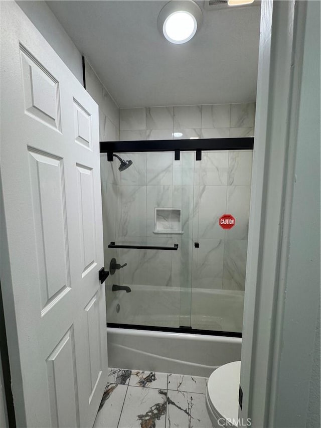 bathroom with toilet and bath / shower combo with glass door