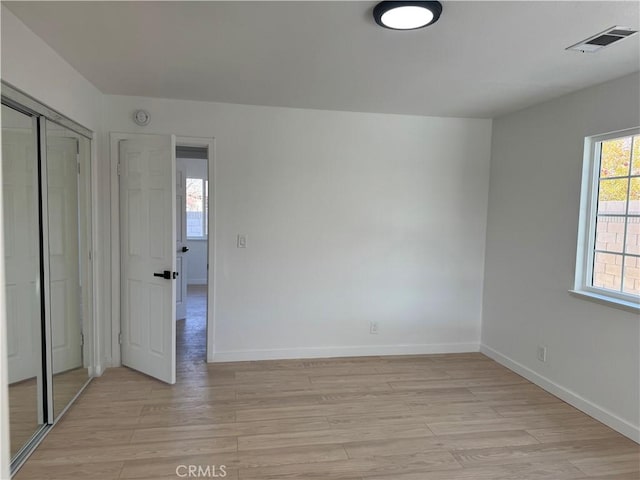 unfurnished bedroom with a closet and light wood-type flooring