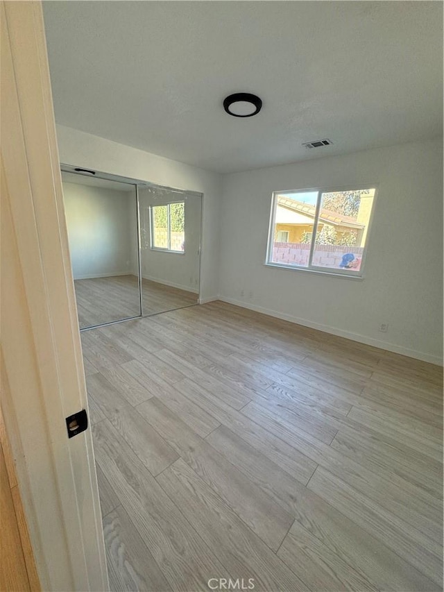 unfurnished bedroom featuring light wood-type flooring and a closet