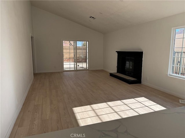 unfurnished living room featuring light hardwood / wood-style floors, lofted ceiling, and a brick fireplace