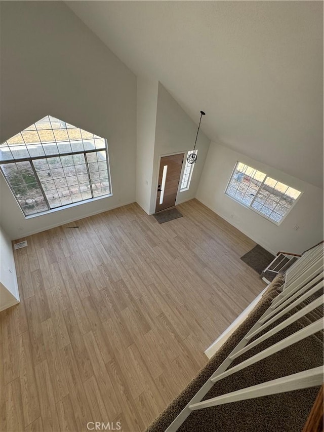 unfurnished living room featuring hardwood / wood-style flooring, high vaulted ceiling, and a healthy amount of sunlight