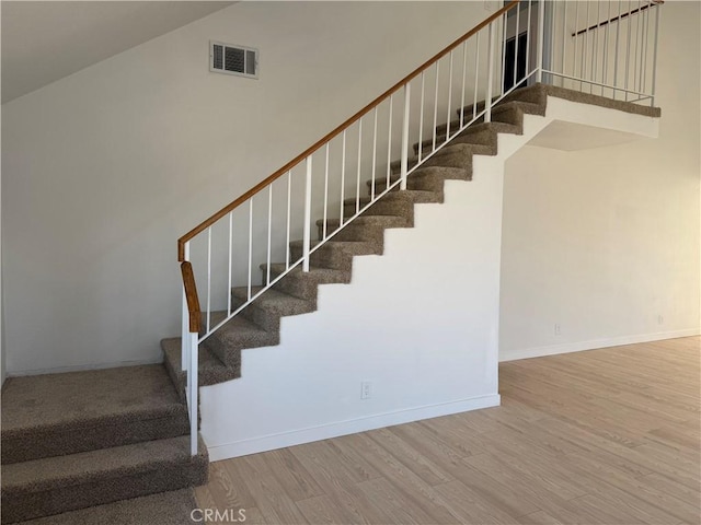 staircase with hardwood / wood-style flooring and a towering ceiling