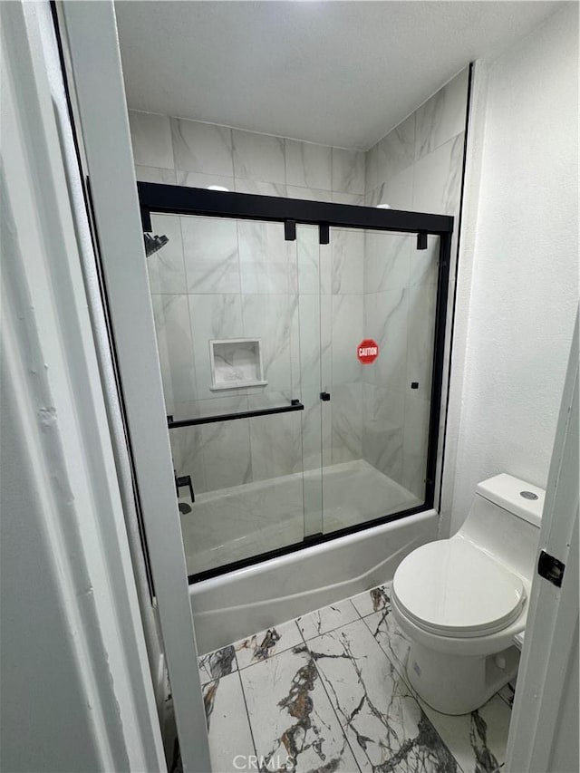 bathroom with toilet and combined bath / shower with glass door