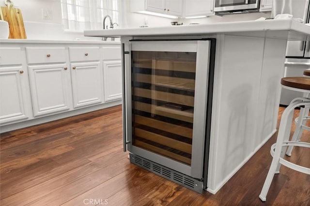 kitchen with white cabinets, sink, beverage cooler, and hardwood / wood-style floors