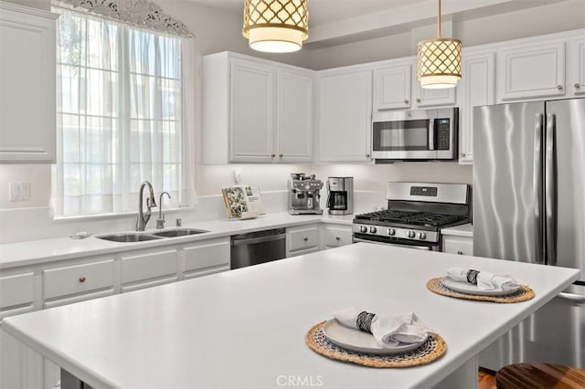 kitchen featuring pendant lighting, appliances with stainless steel finishes, white cabinetry, sink, and a breakfast bar area