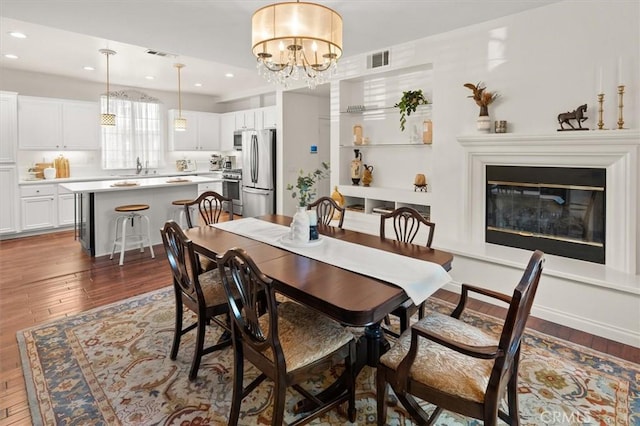 dining room featuring sink, dark hardwood / wood-style floors, and an inviting chandelier