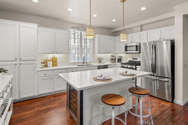 kitchen featuring white cabinetry, sink, stainless steel appliances, and pendant lighting