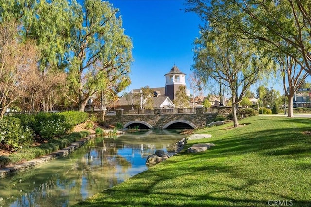 view of property's community featuring a lawn and a water view