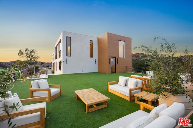 back house at dusk with a yard and an outdoor hangout area