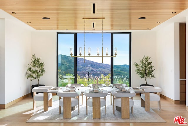 dining room with wooden ceiling, a wall of windows, a mountain view, and light hardwood / wood-style flooring