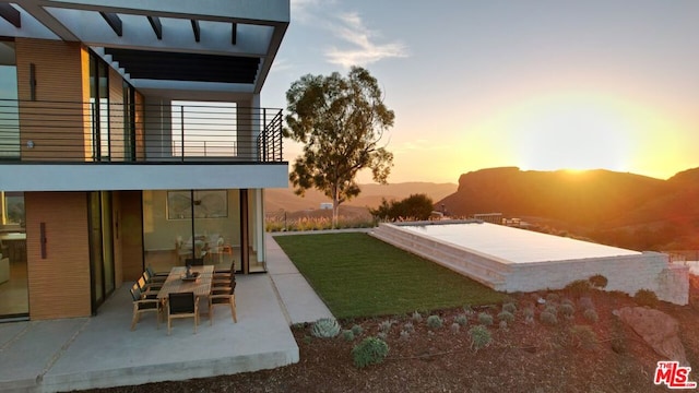 yard at dusk featuring a patio area and a balcony