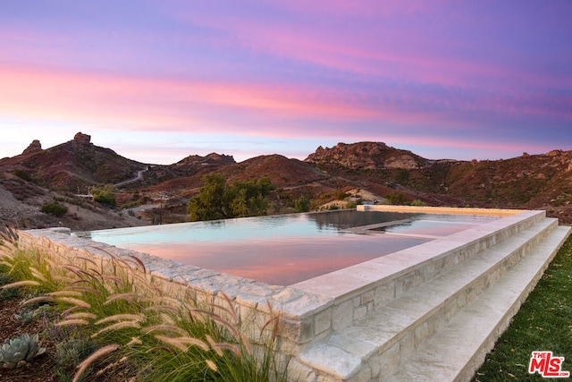 pool at dusk featuring a mountain view