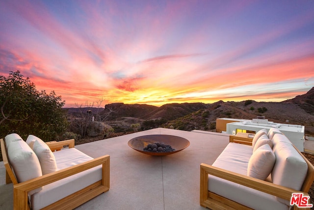 patio terrace at dusk featuring a mountain view and an outdoor living space