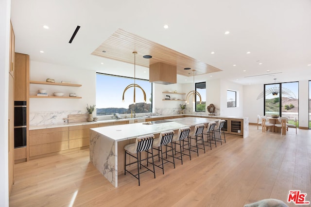 kitchen with hanging light fixtures, light hardwood / wood-style flooring, a center island, and a breakfast bar area