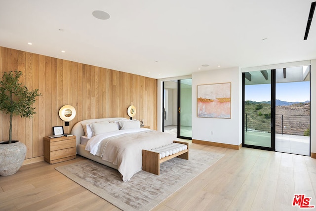 bedroom featuring access to outside, a wall of windows, a mountain view, and light hardwood / wood-style floors