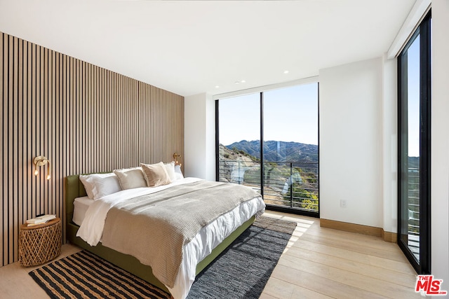 bedroom with light wood-type flooring, a mountain view, expansive windows, and multiple windows