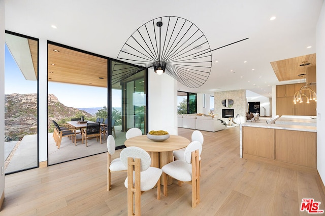 dining area with light wood-type flooring, an inviting chandelier, a mountain view, and floor to ceiling windows