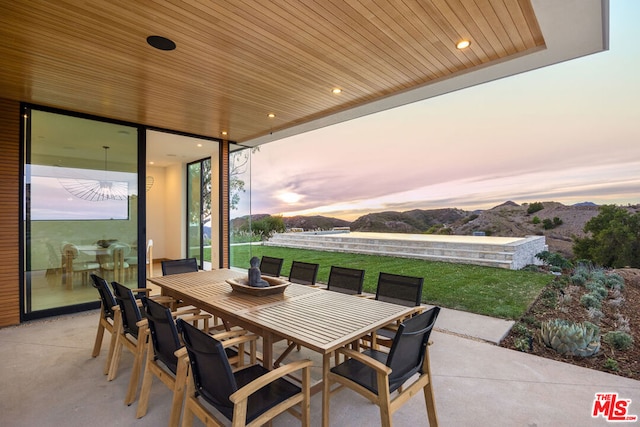 patio terrace at dusk with a mountain view and a yard