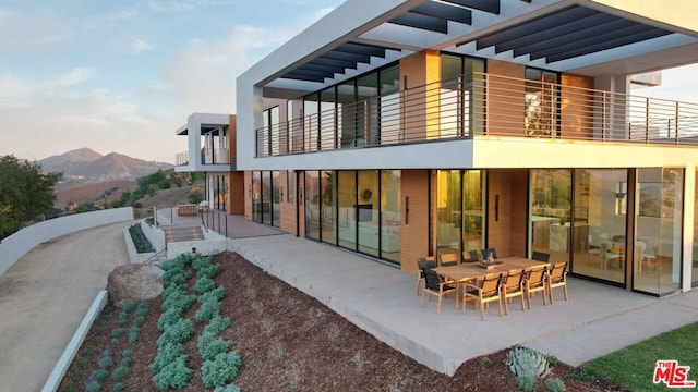 back of house with a balcony, a patio area, and a mountain view