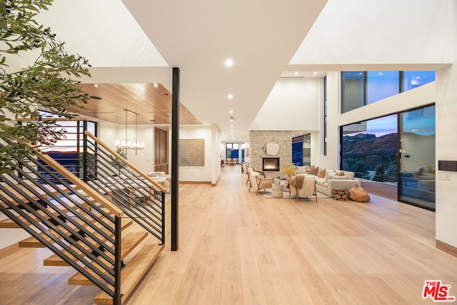 stairway with a towering ceiling, a chandelier, a fireplace, and wood-type flooring