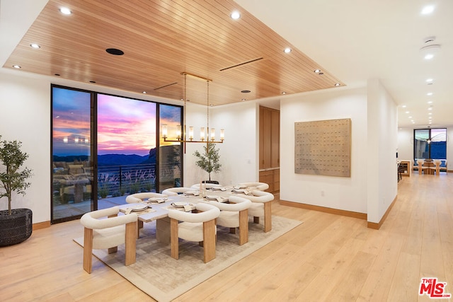 dining area with a mountain view, wood ceiling, a notable chandelier, and light hardwood / wood-style floors