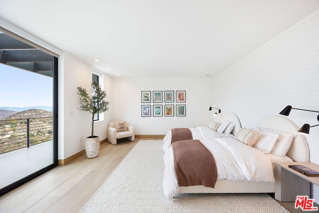 bedroom with a mountain view, light hardwood / wood-style floors, and access to outside