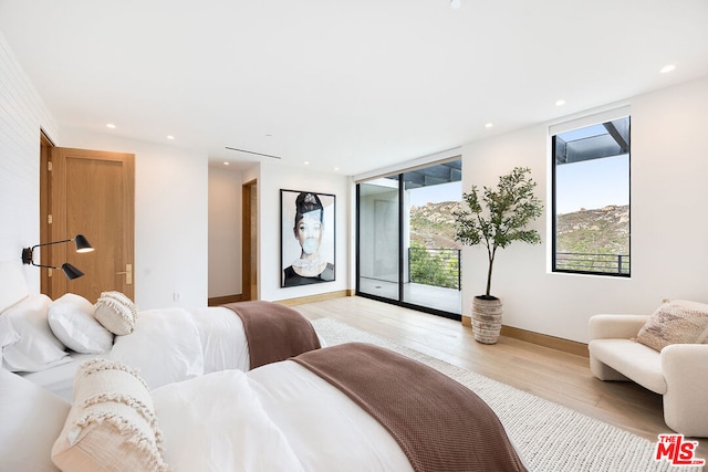 bedroom with a wall of windows, access to outside, and light wood-type flooring