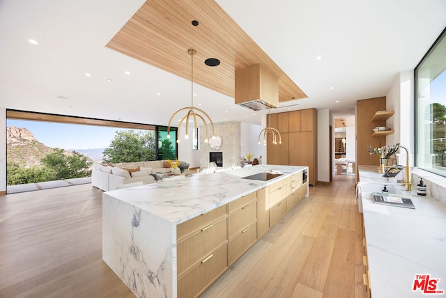 kitchen with floor to ceiling windows, a large island, pendant lighting, light stone counters, and sink