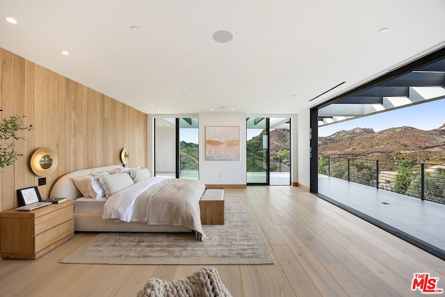 bedroom with wooden walls, floor to ceiling windows, a mountain view, and access to outside