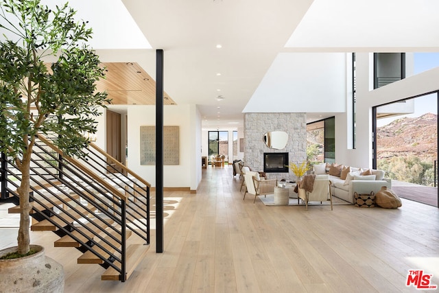 living room with a wealth of natural light, light hardwood / wood-style floors, and a stone fireplace