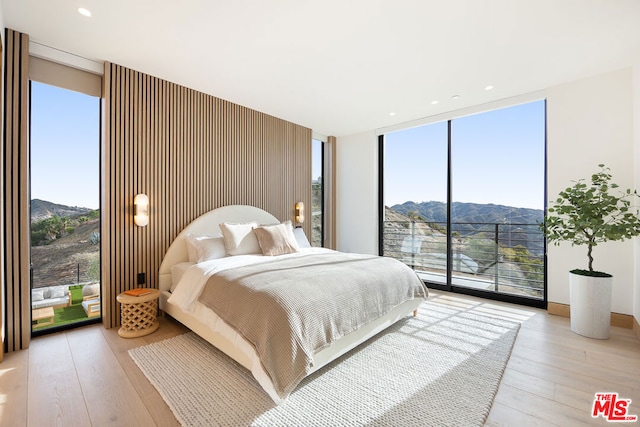 bedroom with a mountain view, floor to ceiling windows, and light hardwood / wood-style flooring