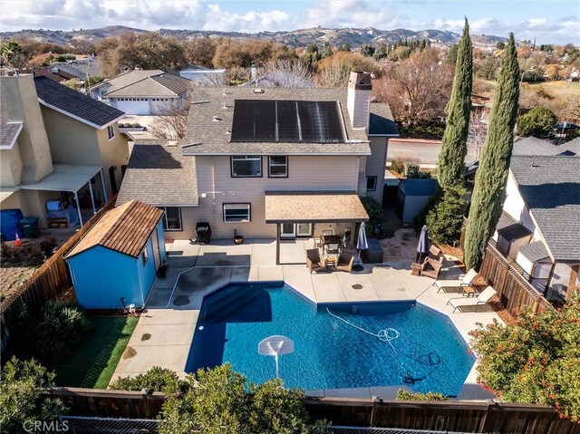 exterior space featuring a fenced in pool, a patio area, a mountain view, and solar panels