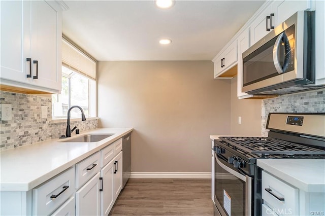 kitchen with white cabinets, sink, stainless steel appliances, and light hardwood / wood-style flooring