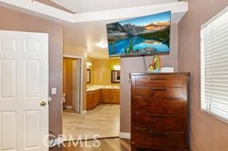 bedroom with connected bathroom and light hardwood / wood-style flooring