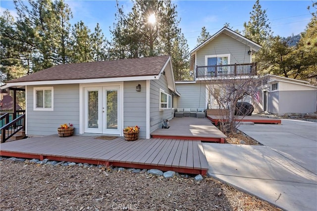 back of property with french doors, a balcony, a deck, and an outdoor structure