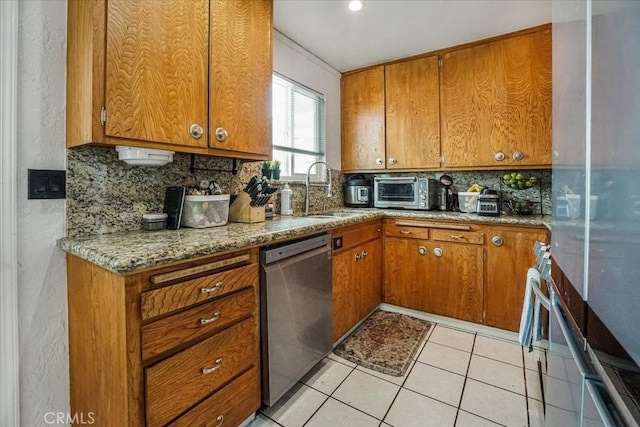 kitchen featuring tasteful backsplash, stainless steel dishwasher, a sink, and brown cabinets