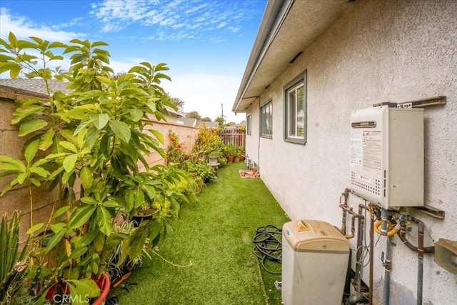 view of yard with water heater and fence