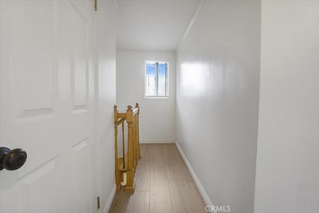 corridor with light wood-type flooring, an upstairs landing, and baseboards