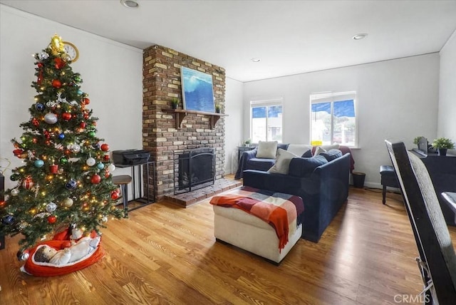 living room with a brick fireplace and wood finished floors