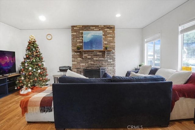 living area with recessed lighting, a brick fireplace, and wood finished floors