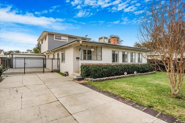 view of front of property featuring an outbuilding, a chimney, stucco siding, concrete driveway, and a front yard