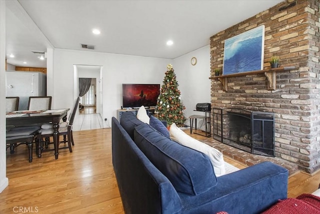 living room featuring a fireplace, visible vents, wood finished floors, and recessed lighting