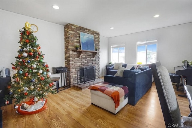 living room featuring a brick fireplace, wood finished floors, and recessed lighting