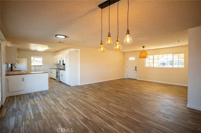 58168 Canterbury St, Yucca Valley, CA 92284 - kitchen featuring appliances with stainless steel finishes, wood finished floors, open floor plan, a textured ceiling, and white cabinetry