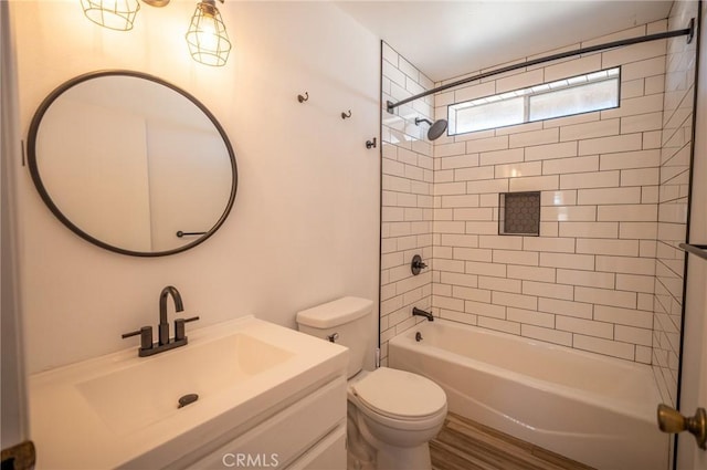 full bathroom featuring hardwood / wood-style floors, vanity, toilet, and tiled shower / bath