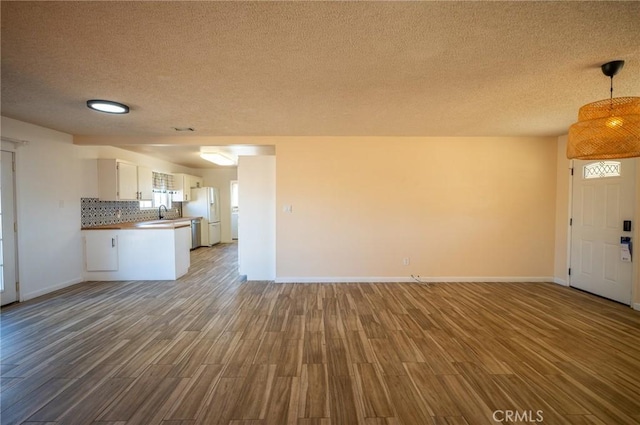 kitchen featuring hardwood / wood-style floors, white cabinets, decorative backsplash, stainless steel fridge, and decorative light fixtures